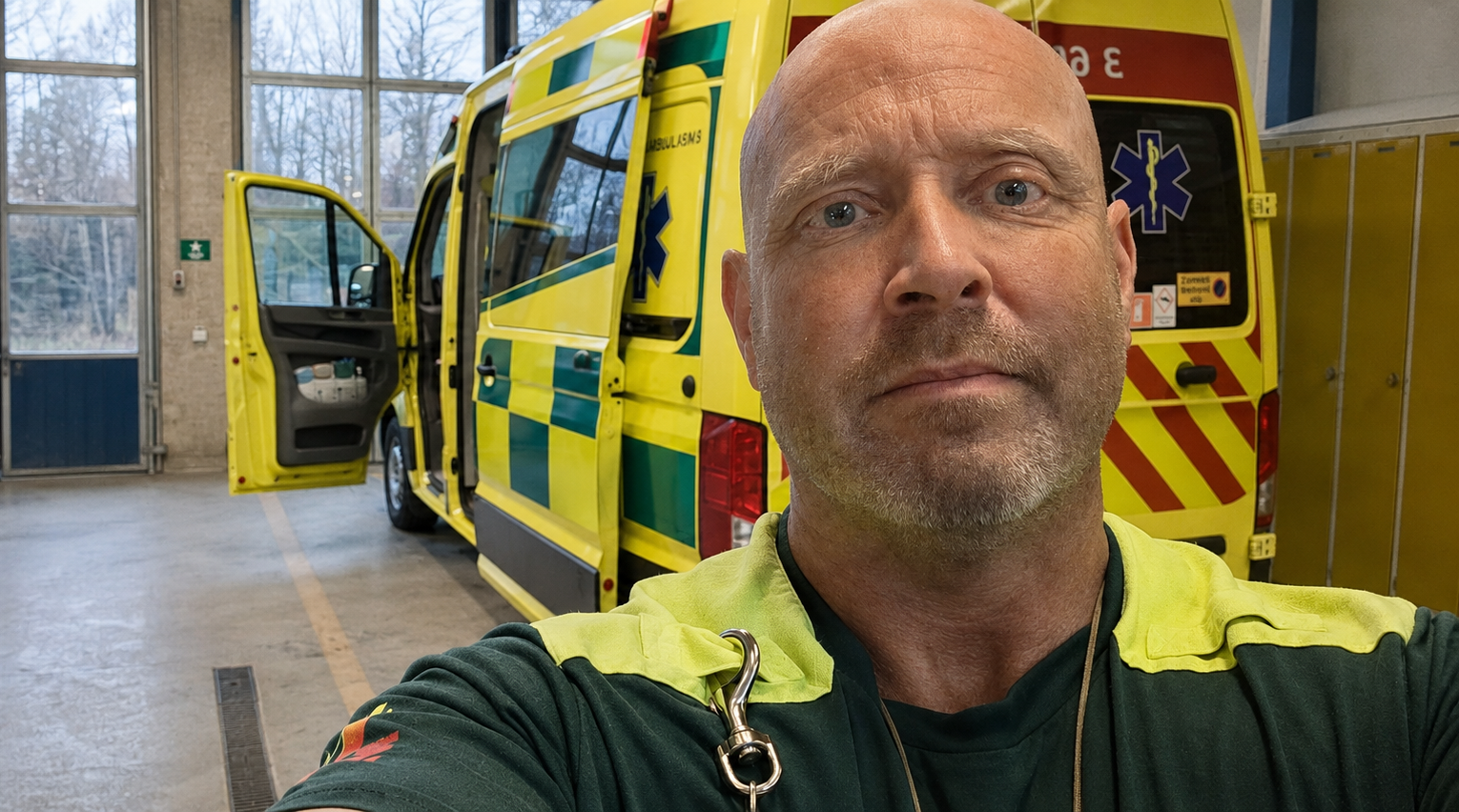 Robert Land i ambulansuniform framför ambulans