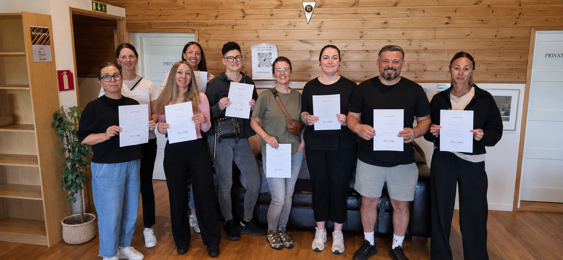 Stor kursgrupp håller upp sina certifikat efter avslutad HLR-utbildning